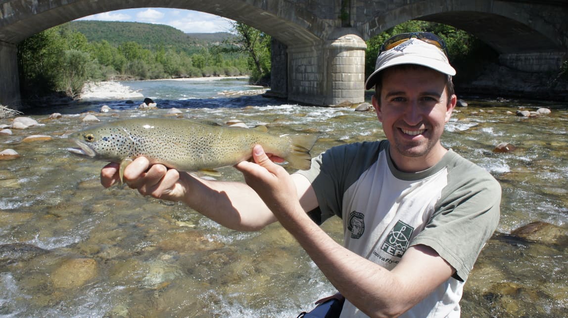 Un pêcheur tenant une truite pêchée en catalogne